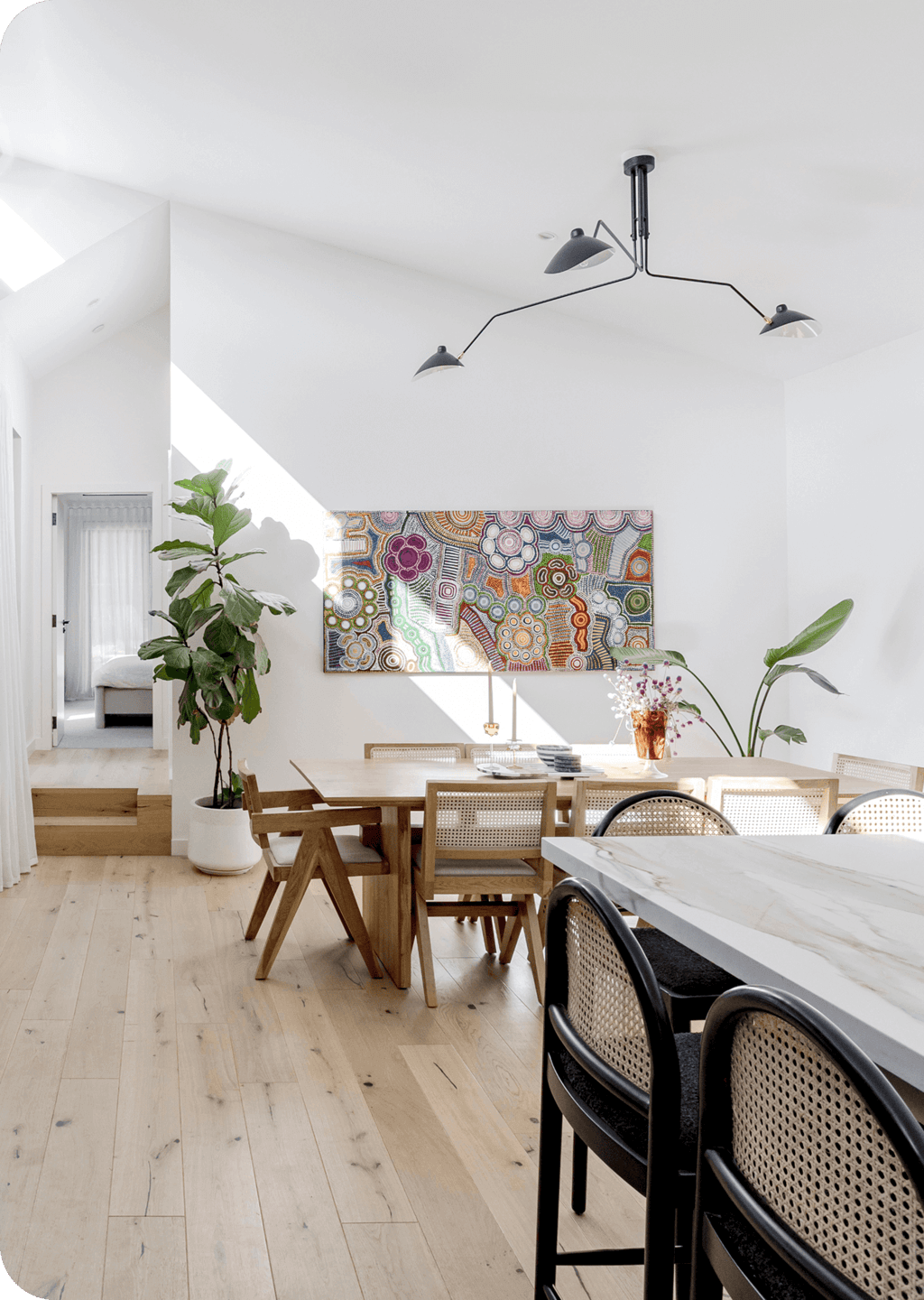 Bright dining room with timber table, indoor plants, and colorful wall art.