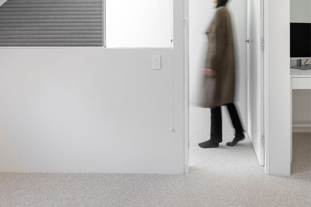 Person walking through a bright, minimalist hallway.